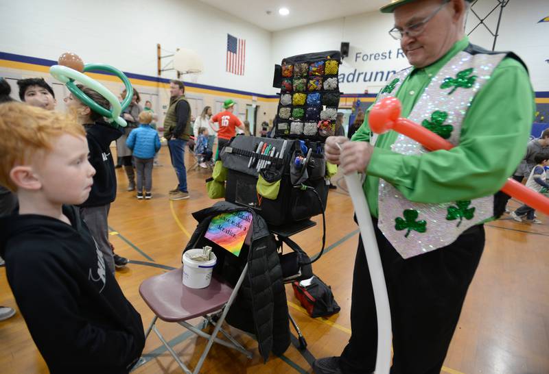 Forest Road 1st grader Charlie Kalus awaits his balloon made by Tom Chyna of Lagrange Park while attending the St. Baldrick fundraiser held Thursday, March 7, 2024.