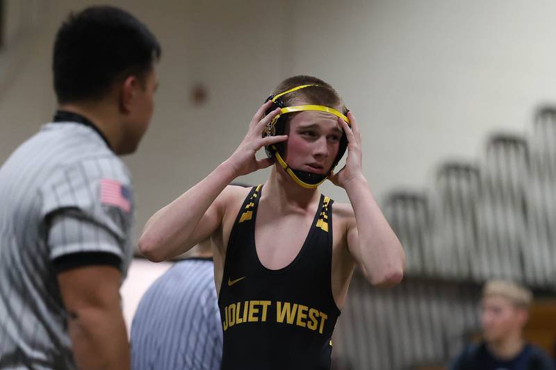 Joliet West’s Jacob Crandall adjusts his head gear after his first period pin against Plainfield South’s Jose Rivas Jr in the 126 pound match on Wednesday, Dec. 3, 2025 in Joliet.