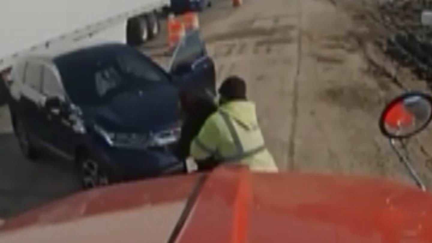 This screen shot from video shows provided by Ozinga show cement truck driver Jeff Hanus helping an unidentified woman who stopped her car and indicated she was choking on Nov. 4, 2023 in Bolingbrook. Hanus says he acted on instinct when he saw her in distress.  (Ozinga via AP)