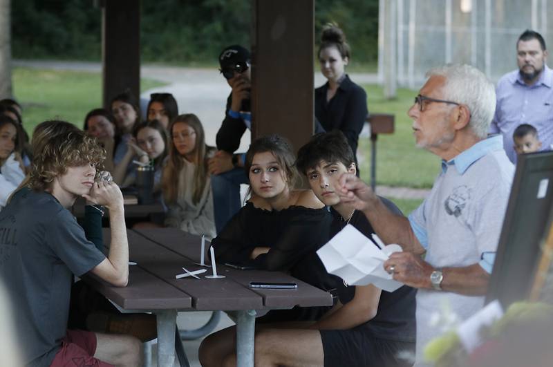 Friends and family listen to Peter Passuntino as he talks about his grandson, Riely Teuerle, during a candlelight celebration for Teuerle on Thursday, August 11, 2022, at Towne Park, 100 Jefferson Street in Algonquin. Teuerle was killed in a car crash in Lake in the Hills on Tuesday. Over 100 family members and friends gathered at the park to remember and celebrate Teuerle’s life.