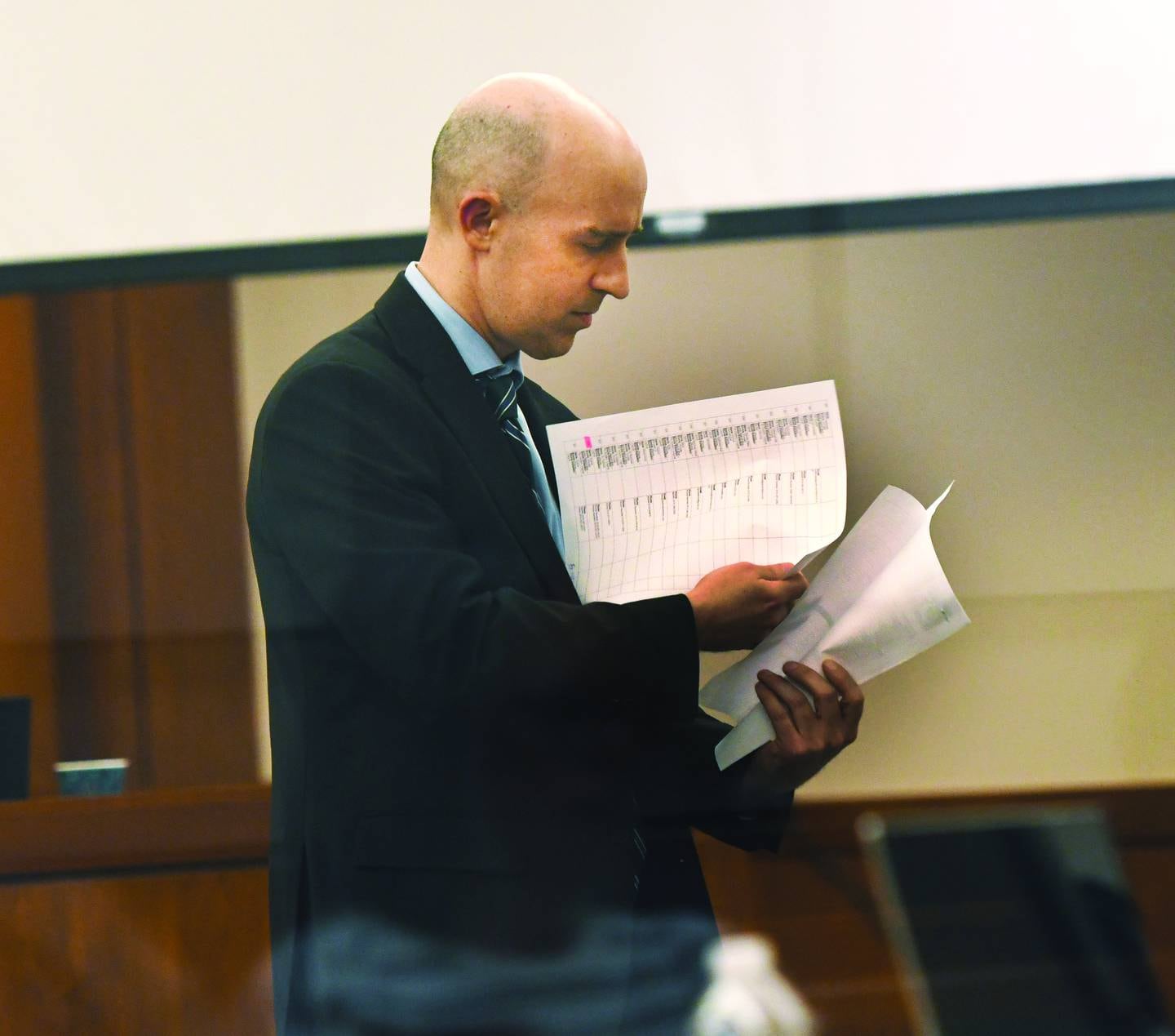 Assistant Ogle County State's Attorney Matthew Leisten examines documents as he questions Illinois State Police Special Agent Nate Macklin on Friday, Jan. 16, 2026 about cell phone messages extracted from Duane C. Meyer's phone in 2016.