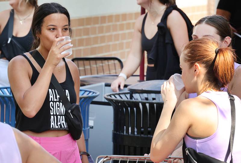 Northern Illinois University student volunteers try to stay cool with some water as they help new arrivals get their things moved into their rooms Wednesday, Aug. 23, 2023, during move-in day in front of the Fanny Ruth Patterson Complex at NIU in DeKalb.