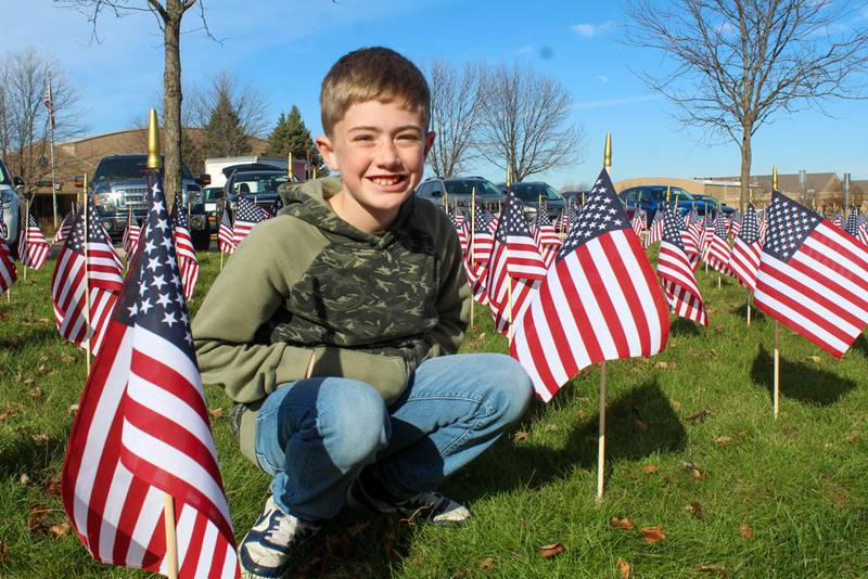 Henry Franzen, a fifth grade student at River View Elementary School, raised $2,060 for the Disabled American Veterans Field of Flags. Commemorative flags will remain on school grounds through Thursday. Henry Franzen crouches in the Field of Flags at the school on Friday, November 8, 2024.