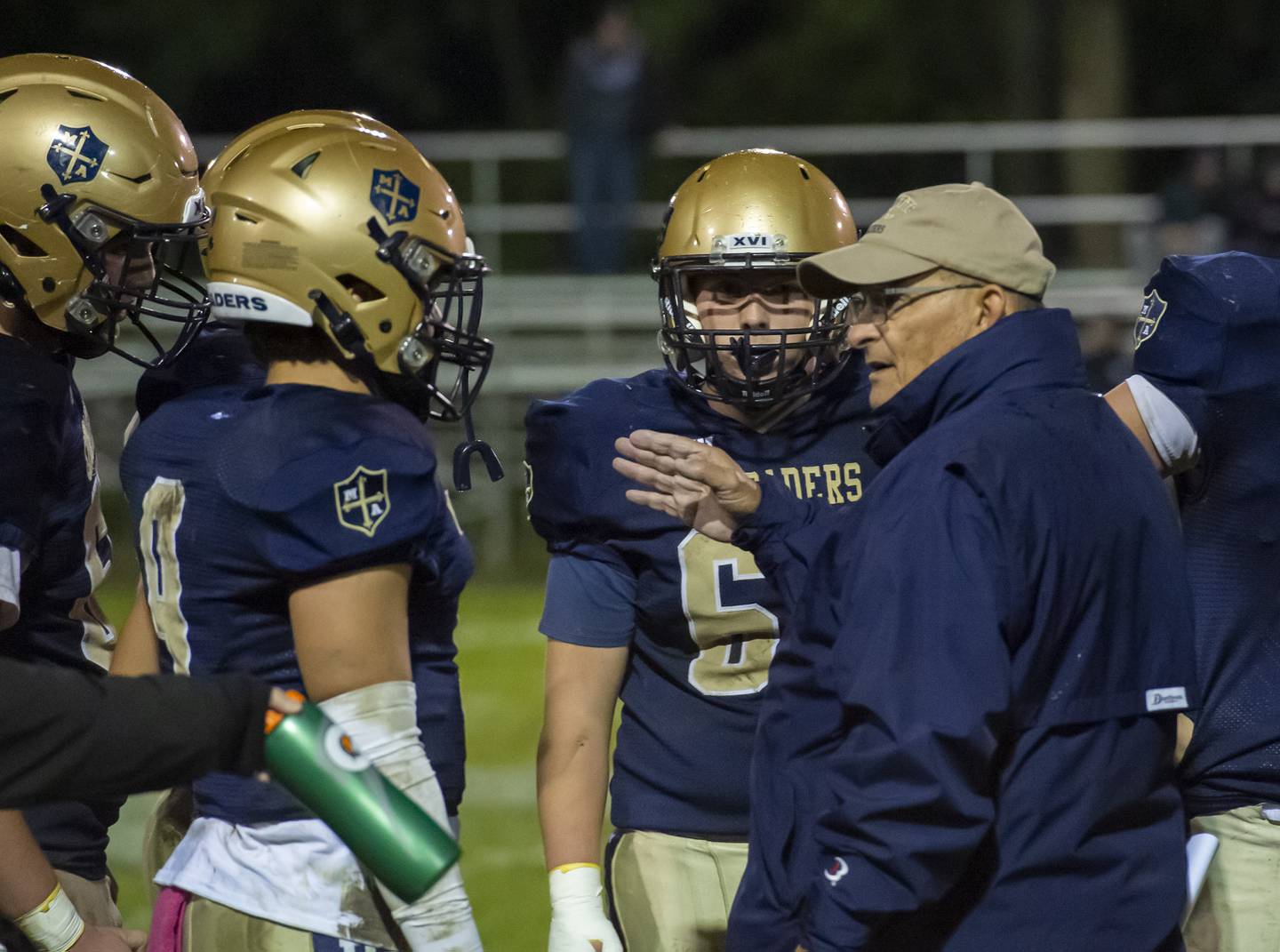 Marquette head coach Tom Jobst discusses a play call with quarterback Alex Graham (left) during the 1A playoff game against Princeville on Friday.