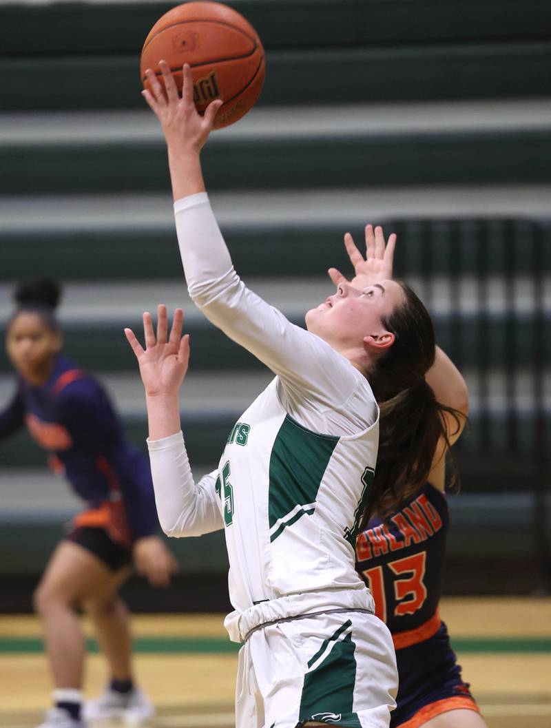 Kishwaukee College's Emily Gilbert shoots a reverse layup in front of Highland Community College's Marie-Louise de Jong during their game Thursday, Jan. 11, 2024, at Kishwaukee College in Malta.