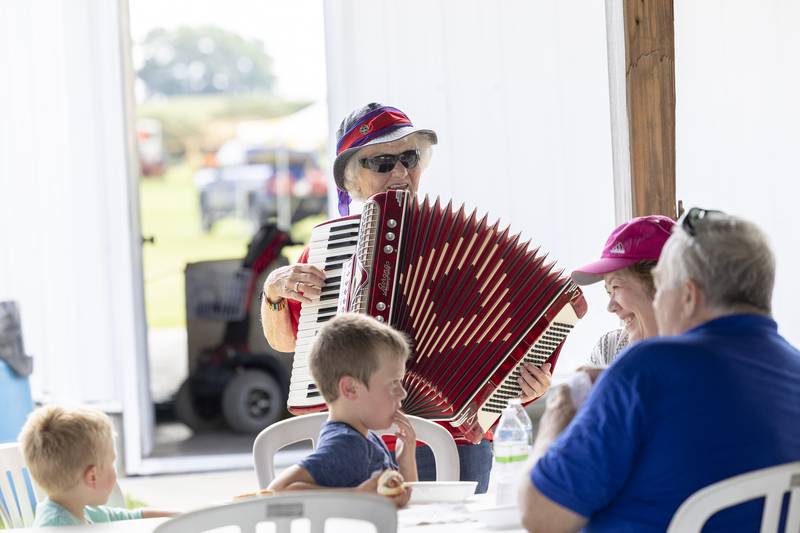 Bev Kearns entertains a family with a rendition of “When the Saints Go Marching In” Saturday, Aug. 3, 2024 at the Living History Antique Equipment Association’s farm show.