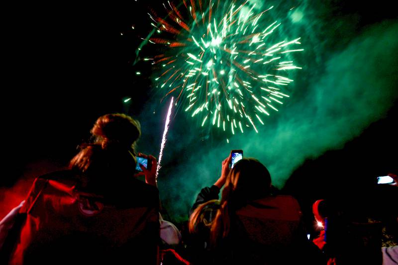 Spectators document the fireworks at the Aroma Park Boat Club's Cheeseburgers & Fireworks event in 2021.