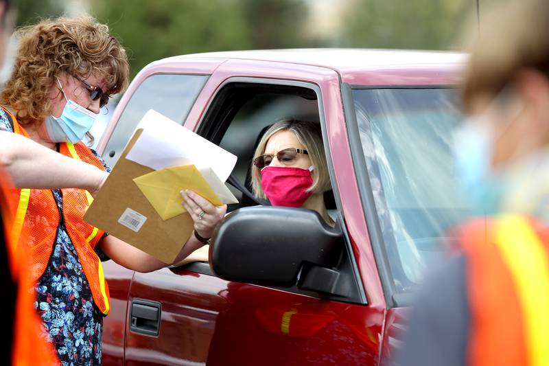 Volunteer Julie Walker (left) helps Roni Dutro of Sugar Grove pick up a lunch for seniors at the Sugar Grove Community Building on April 28. The monthly senior lunch and games day was switched to a drive-thru only event due to the Covid-19 crisis. The Kane County Sheriff's Department also donated activity bags to the seniors.