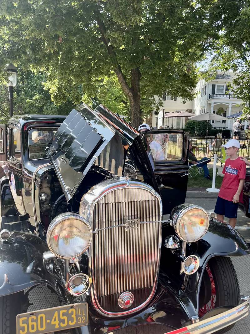 Bruce Eiseman helps children into his father's restored 1932 Buick at Geneva's Concours d’Elegance car show.