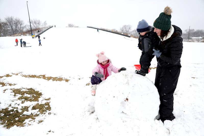 Natalie Bielski of Wheaton helps her kids, Juliette, 5, and Jonathan, 2, climb a mound of snow at Northside Park in Wheaton on Wednesday, Jan. 25, 2023.
