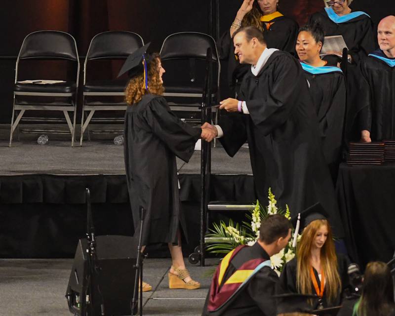 A St. Charles East graduates accepts her diploma on Monday, May 18, 2026, at the Convocation Center in DeKalb.