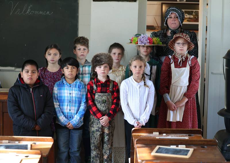 Southeast Elementary School third grade teacher Jami Sauber along with some of her students pose for a photo with the typical expressionless look from photos of the era in the front of the classroom Tuesday, Nov. 4, 2025, during a field trip to North Grove School, a one-room schoolhouse from 1878 in Sycamore.
