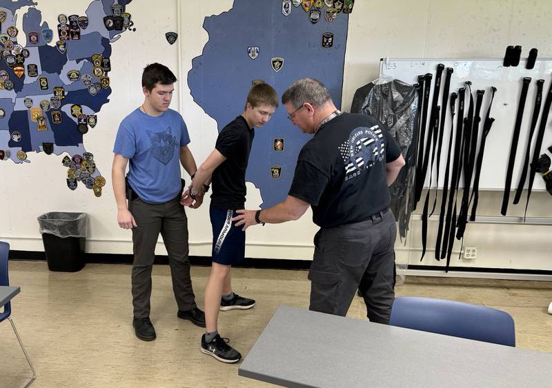 Instructor Brent Dite shows two students how to properly apply handcuffs while keeping themselves safe during a traffic stop.