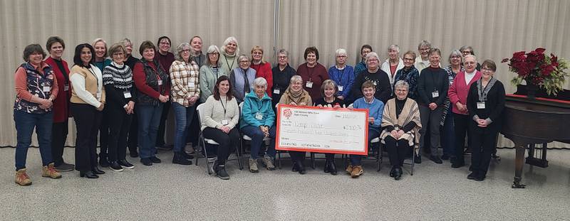 100 Women Who Care Ogle County pose with the mock check they presented to Camp Cedar. The group of women  join together to donate to charities within Ogle County.