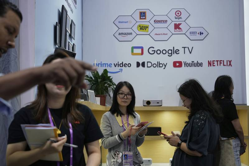 Sales rep promote projectors at the 137th Canton Fair in Guangzhou in southern China's Guangdong province on Tuesday, April 15, 2025. (AP Photo/Ng Han Guan)