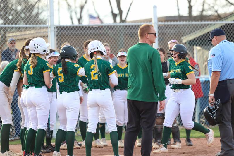 Grant Park players surround home plate to celebrate a grand slam by Cheyenne Hayes, right, to secure the Dragons' 12-2 victory over Milford/Cissna Park in six innings on Wednesday, March 25, 2026.
