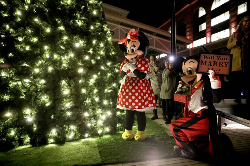 Jacob Rosada, dressed as Mickey Mouse, proposes to his girlfriend, Gabrielle Hill, dressed as Minnie Mouse, during the City of Wheaton’s Christmas Tree Lighting Ceremony in downtown Wheaton on Friday, Nov. 25, 2022.