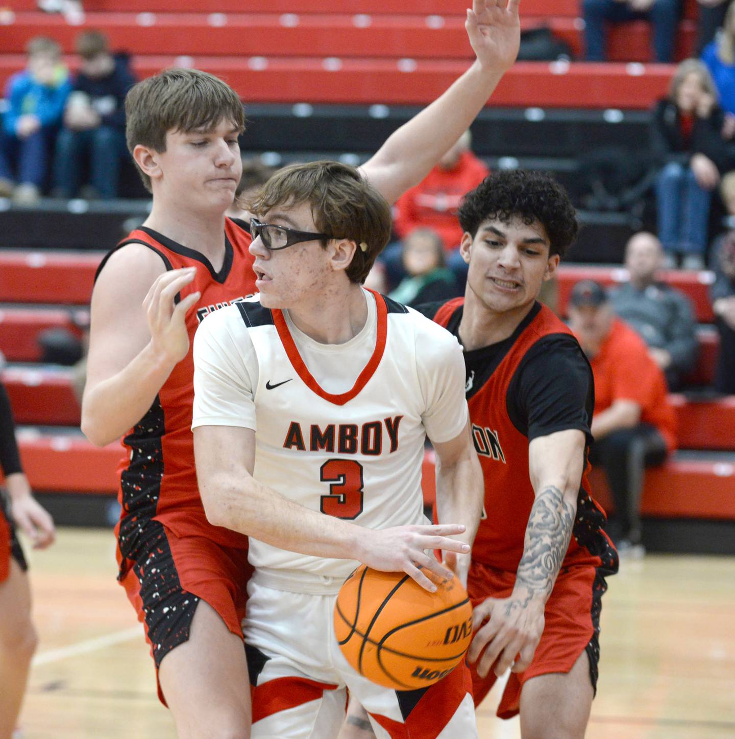 Amboy's Brody Christofferson (3) looks to pass as Fulton's Landen Leu (10) and Jace Bielenberg (3) defend on Friday, Jan. 17, 2025 at Amboy High School.