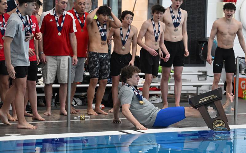 On his first attempt, Hinsdale CentralÕs Brody Marcet slips and falls on the pool deck and the state championship trophy falls into the water at the conclusion of the boys state swimming and diving finals at FMC Natatorium on Saturday, Feb. 24, 2024 in Westmont. He was not injured and he succeeded on the second try.