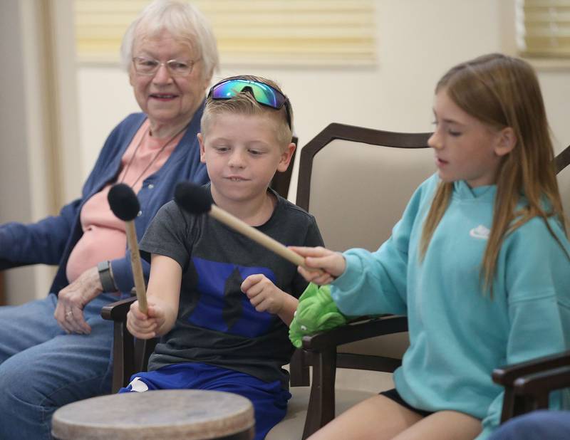 Lincoln Elementary School students Duke Engel and Tennyson Sayler play a drum while resident Julie McCutchen watches during a drum circle on Friday, Oct. 17, 2025 at Greenfield Retirement Home in Princeton. The drum circle was hosted by Eric Swanson of Chicago, through his business Drum Impact. The students learned how to make rhythm, play instruments, music therapy, collaboration and converse with the residents.