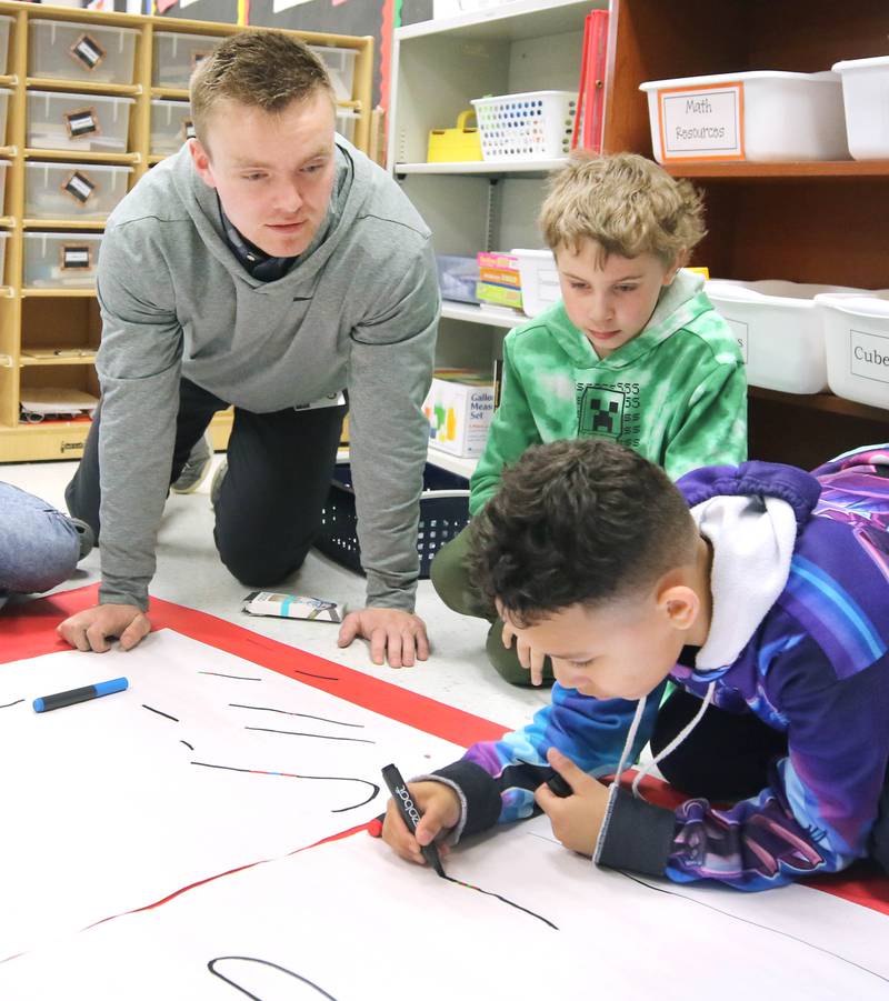 Jacob Winters, fourth grade teacher at South Prairie Elementary School, works with Jaxon Boelk (center) and Amari Morris on a robotics lesson Wednesday, April 6, 2023, at the school in Sycamore.