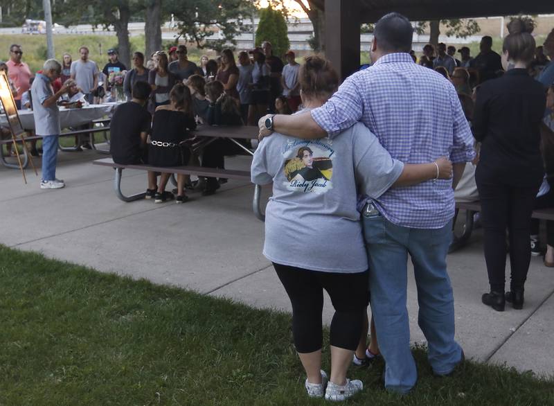 Friends and family listen to Peter Passuntino as he talks about his grandson, Riely Teuerle, during a candlelight celebration for Teuerle on Thursday, August 11, 2022, at Towne Park, 100 Jefferson Street in Algonquin. Teuerle was killed in a car crash in Lake in the Hills on Tuesday. Over 100 family members and friends gathered at the park to remember and celebrate Teuerle’s life.