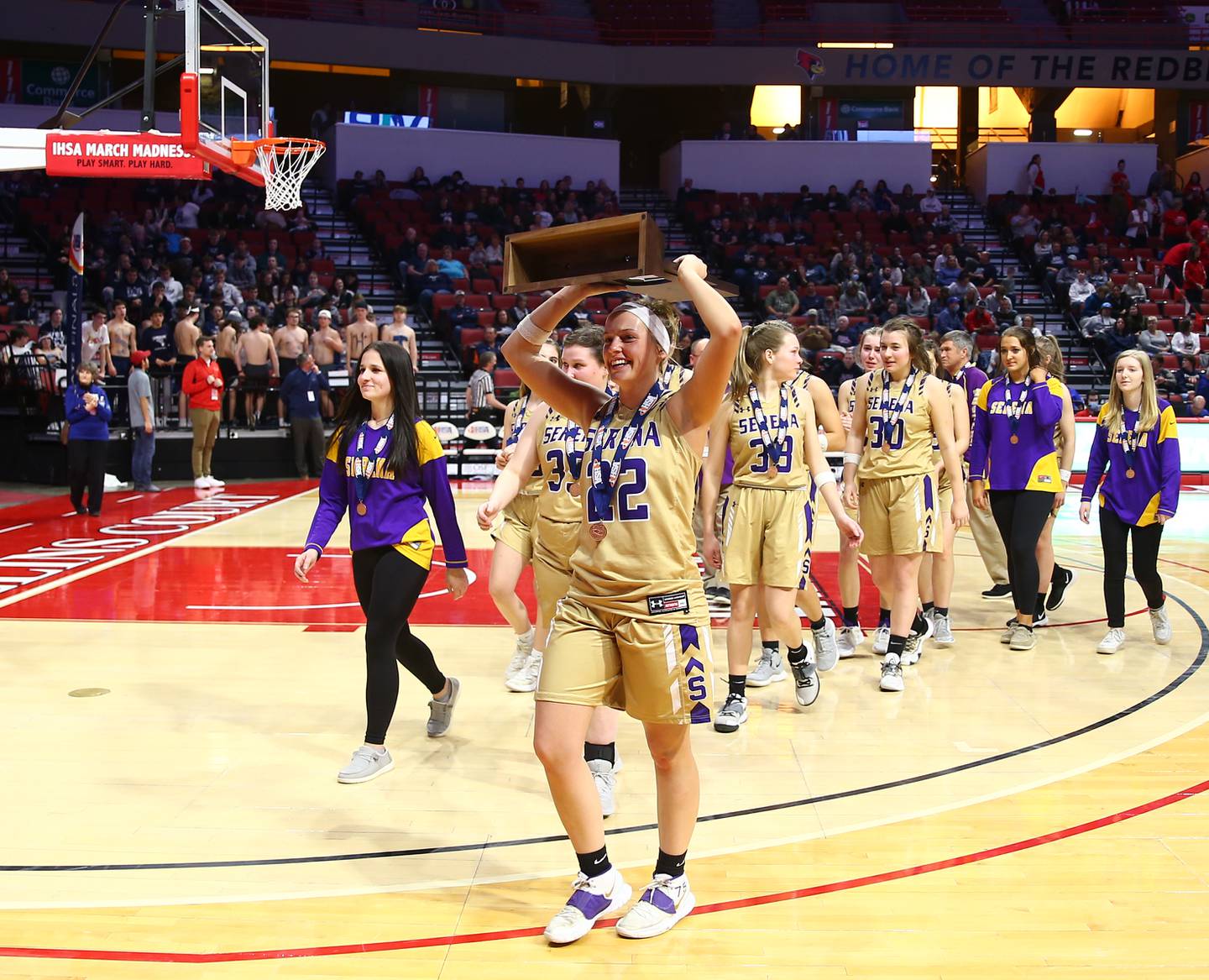 Serena's Katie Baker (22) lifts the fourth-place trophy after the Class 1A girls basketball third-place game on Thursday, March 3, 2022, at Redbird Arena in Normal.