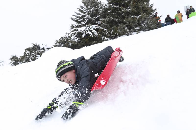A sledder wipes out after hitting a jump on Sunday, Jan. 31, 2021, at Cene's Four Seasons Park in Shorewood, Ill. Nearly a foot of snow covered Will County overnight, resulting in fun for some and challenges for others.