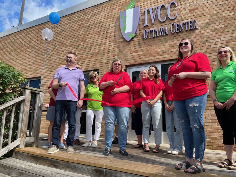 Donna Reynolds (holding scissors), tourism operations manager for the Ottawa Visitor Center, cuts the ceremonial ribbon Saturday, July 6, 2024, at the "We The People" exhibit commemorating the Sept. 11 terror attacks. The exhibit is on display through July 31 at the IVCC annex in Ottawa.