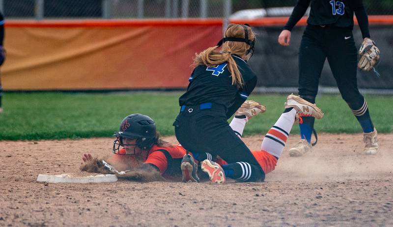 St. Charles East's Katie Morgan (23) slides under the tag from St. Charles North's Julia Larson (4) for a steal during a softball game at St. Charles East High School on Monday, April 25, 2022.