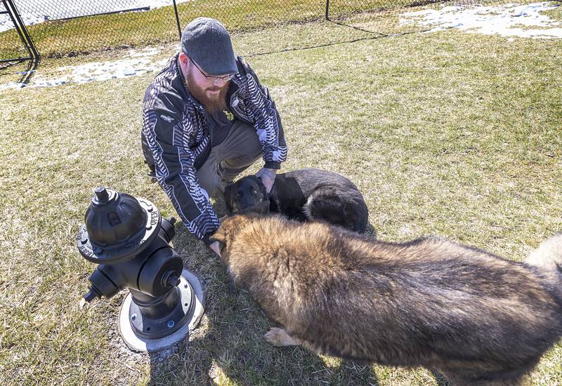 Raven and Cyrus hang with their owner, Marshall Doane, on Thursday, March 19, 2026, at Dogwood Acres in Sterling. Doane, an advocate for the dog park, helped secure every dog’s favorite “watering hole,” a fire hydrant. CIMCO donated a pair of hydrants to the park, one for the small dog area and one for the larger pups.
