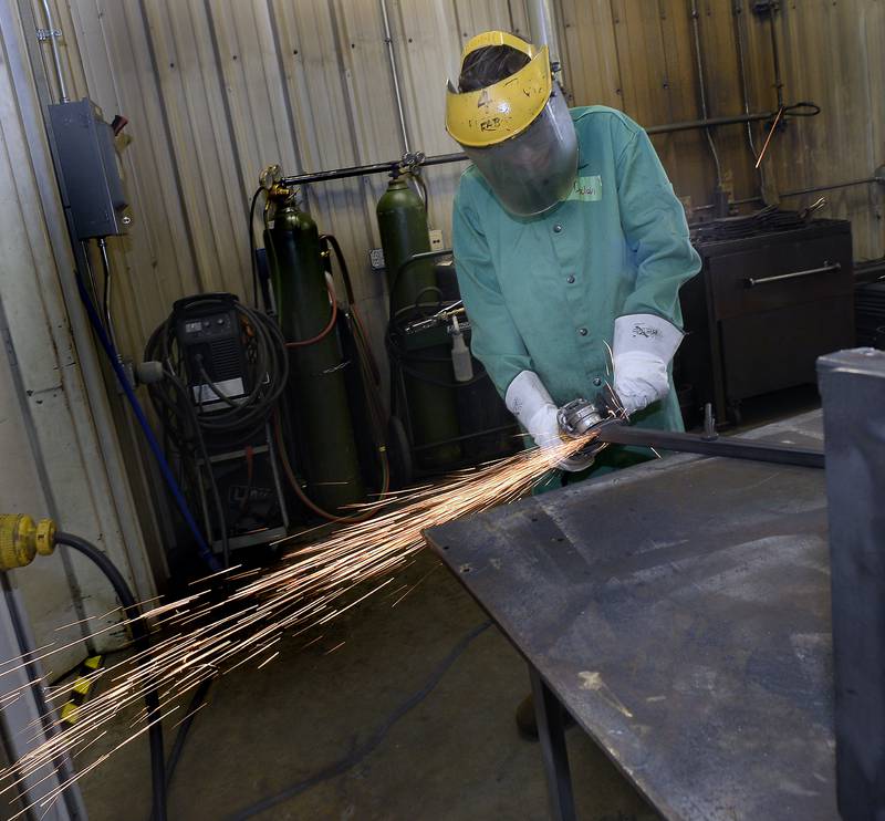 Declan Kulpa shaves down a leg for a side table Wednesday, July 28, 2023, during SPARK Junior Welding program, part of Illinois Valley Community College's summer camp program.
