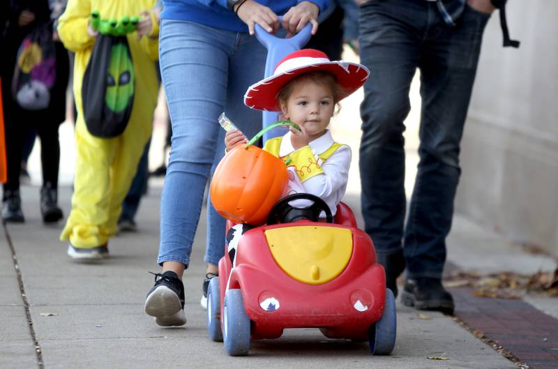 Adeline Smith, 2, dressed as Jessie from Toy Story, goes trick-or-treating at Geneva businesses on Thursday, Oct. 27, 2022.