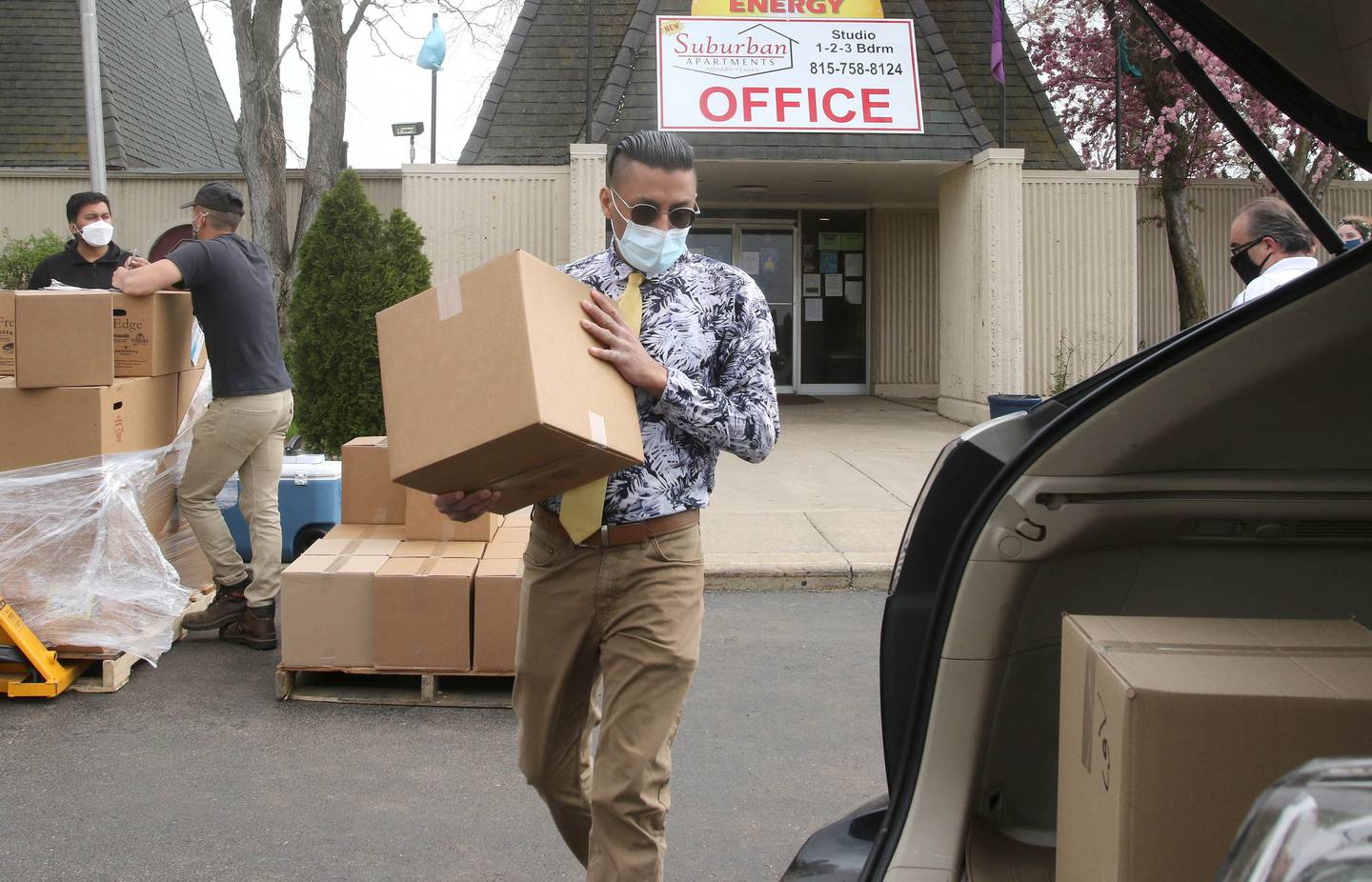 Amit Sharma, with Suburban Apartments, carries a box of food to a car at the complex in DeKalb Wednesday during a food distribution by DeKalb County Community Gardens.