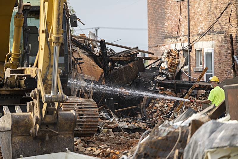 Patrick Burke hoses down the area for dust control Tuesday, Sept. 5, 2023. It’s expected to take two days to demolish, fill in the basement and haul away any debris.