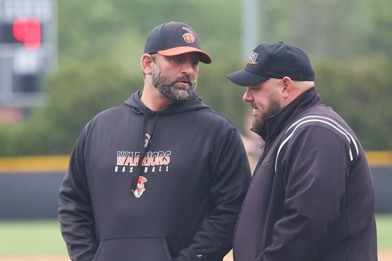 Lincoln-Way West head coach Jake Zajc talks with an umpire between innings against Lincoln-Way Central on Monday, May 8, 2023 in New Lenox.
