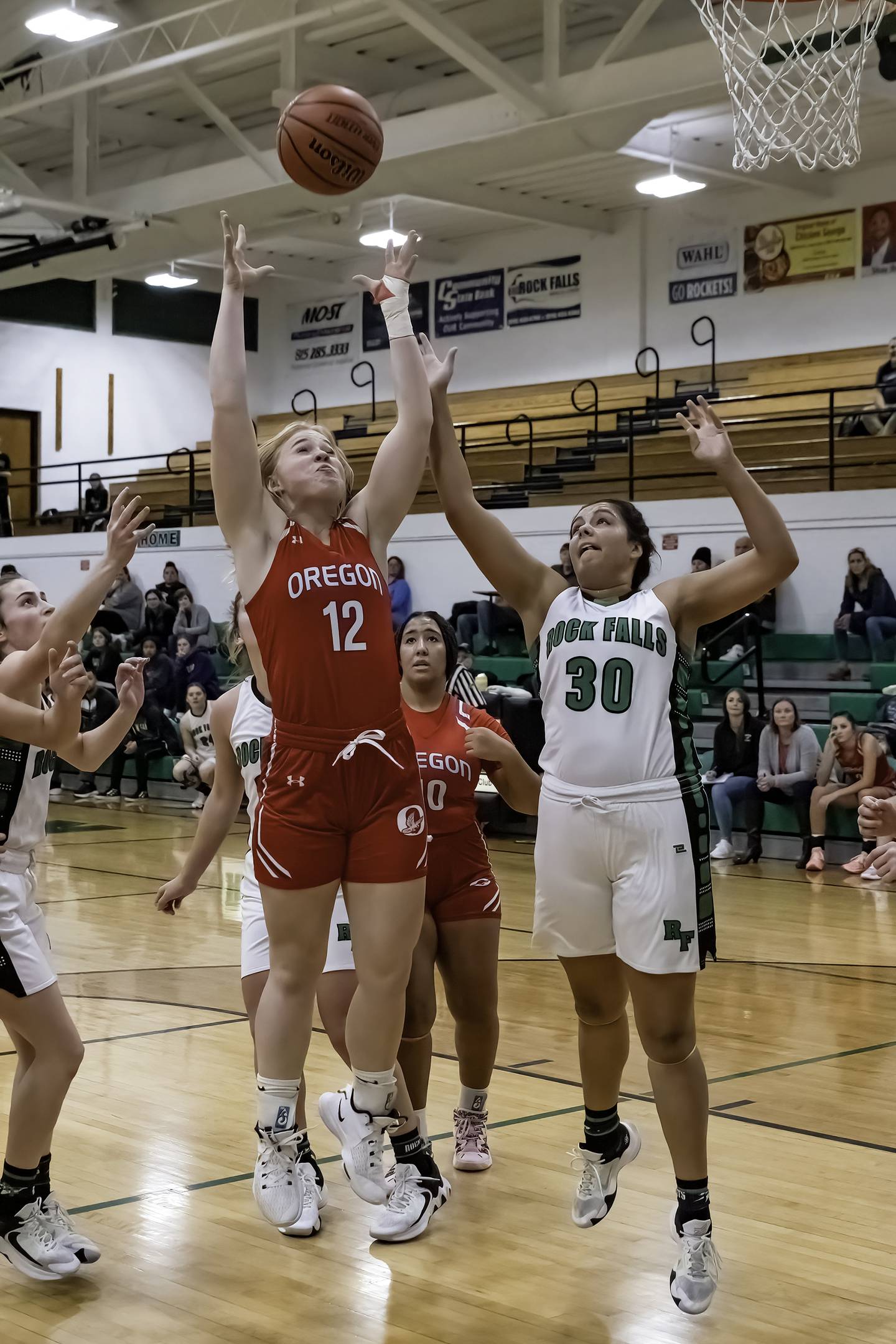 Oregon's Liz Mois (12) goes up for a rebound over Rock Falls' Taylor Reyna (30) during their Big Northern Conference game Friday night at Tabor Gym.