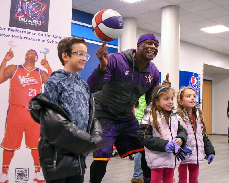 Rocky Aiyash, 9, left, pose for a photo with twin sisters Leyla and Alia,6, of Downers Grove, along with Harlem Wizard Space Jam before the start of the game on Sunday Jan. 19, 2025, held at Downers Grove South High School.