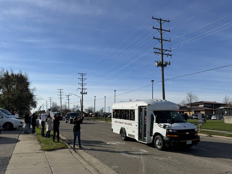 A bus full of state-bound Morris Community High School cross country runners head north on Union Street with their family and friends cheering them on.