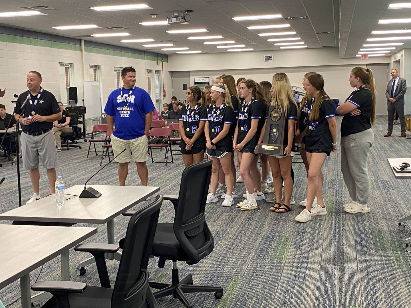 St. Charles North High School softball coaches Tom Poulin, left, and Thijs Dennison, right, along with the St. Charles North softball team celebrate the team's first state title during Monday's St. Charles School Board meeting.