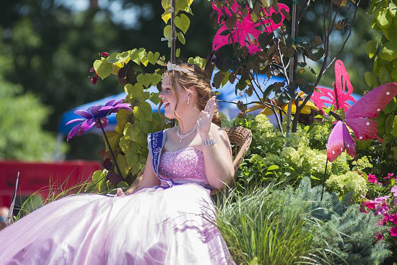 Petunia queen Kendall Fassler waves from a float Sunday, July 3, 2022 as it moves through the parade.