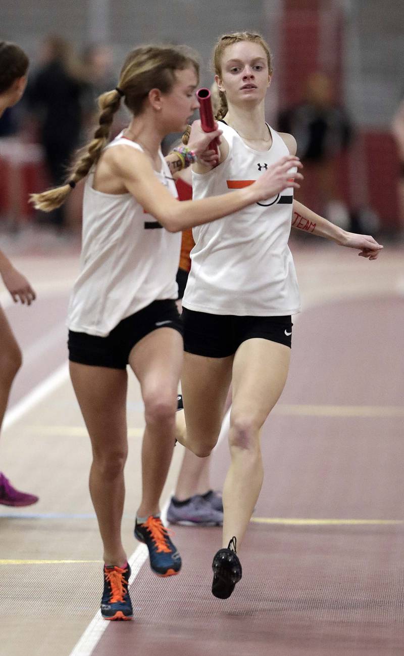 Wheaton Warrenville South’s Annie Macabobby hands off the baton to Nicole Poglitsch in the 4x800 during the DuKane Girls Indoor Championship track meet Friday March 18, 2022 in Batavia.