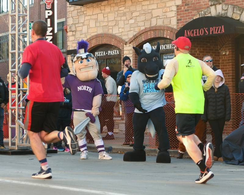 Downers Grove North and South mascots cheer on participants who took part in the Grove Express 5k race held in downtown Downers Grove on Thursday Nov. 23, 2023.