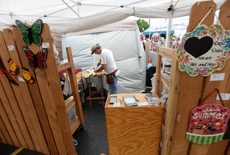 Bill Coleman of Great Lakes adds wings to a horse fly he created during the La Grange Craft Fair Saturday July  16, 2022.