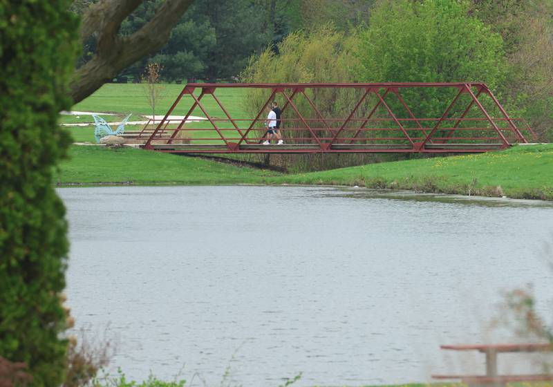 People walk on the bridge along the new walking path on Thursday, April 16, 2026 at Baker Lake in Peru. The project is now complete and the park is back open to the public. Construction work began last October and included a 10-foot-wide concrete path, with secondary concrete paths also added, connecting the new parking lot near Lighted Way to the parking lot, playground, and shelter on the west side of Baker Lake. The new path is 2 feet than the current one.