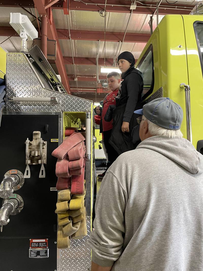 Izan Bradley and Jacob Binert learn about the controls on one of the Tiskilwa fire engines from Tiskilwa Fire Chief Randy Philhower.