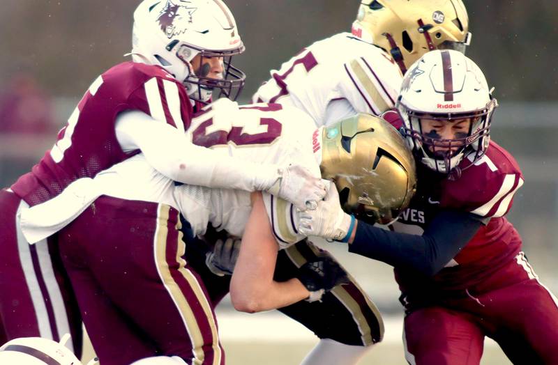 Prairie Ridge’s Joseph Vanderwiel, right, and Giovanni Creatore, left, take care of St. Ignatius’ Vinny Rugai in Class 6A football playoff semifinal action at Crystal Lake on Saturday.