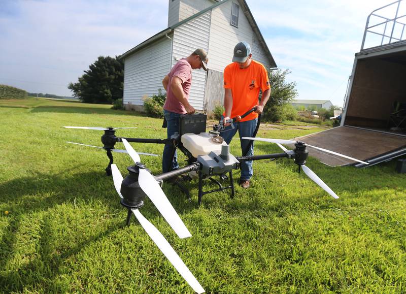 Tyce Barkman of Sweetwater Technologies inserts a new battery into a DJ AGRAS T40 drone as Brodie Jagers fills DRONEZONE, a product containing fungicide, insecticide, and herbicide applications into a 18.5 gallon tank on a farm on Wednesday, Aug. 6, 2025 outside of Amboy. New hi-tech drone technology throughtout Northern Illinois is providing more accurate and precise aerial application then the average crop duster.  The spray airplane hasn’t made it’s final approach yet but there's a possibility it may disappear in our lifetimes.