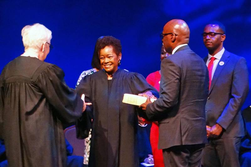 Justice Mary Jane Theis, left, administers the oath of office to Lisa Holder White, making her the first Black woman to serve on the Illinois Supreme Court. Holder White's husband James White holds a Bible while their son Brett White looks on.