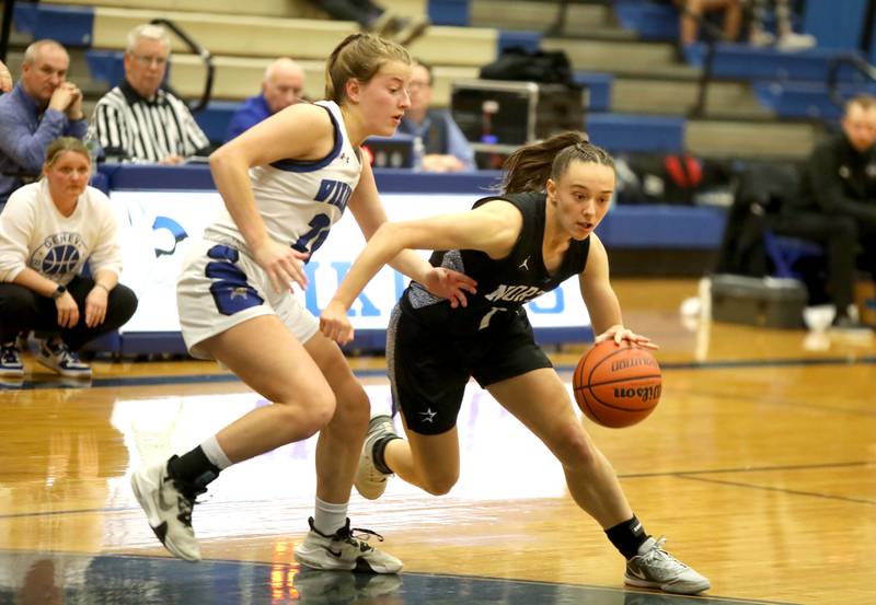 St. Charles North’s Laney Stark drives toward the basket away from Geneva’s Caroline Madden during a game at Geneva on Tuesday, Feb. 6, 2024.